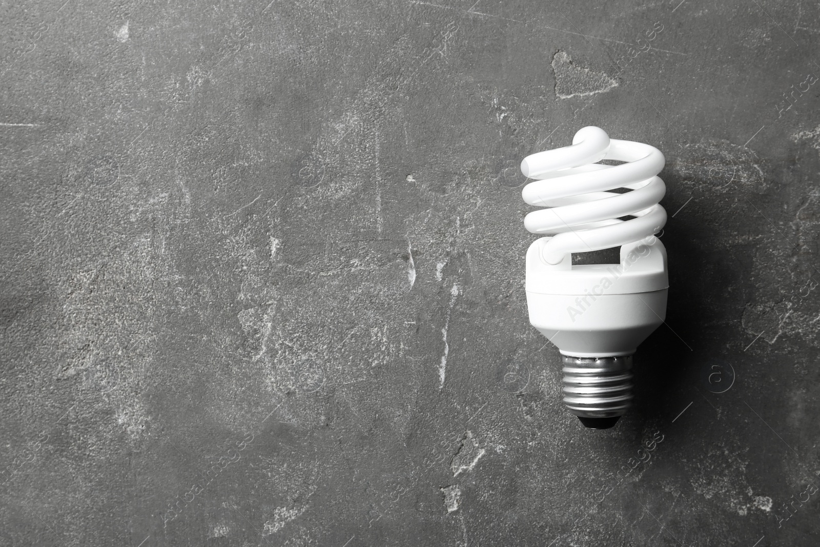 Photo of New fluorescent lamp bulb on grey stone surface, top view. Space for text