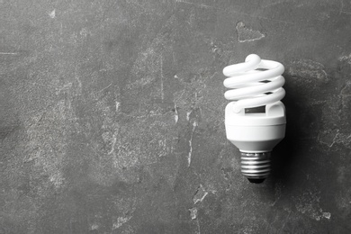 New fluorescent lamp bulb on grey stone surface, top view. Space for text