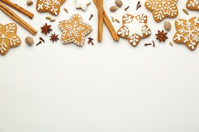 Photo of Tasty Christmas cookies with icing and spices on white background, flat lay. Space for text