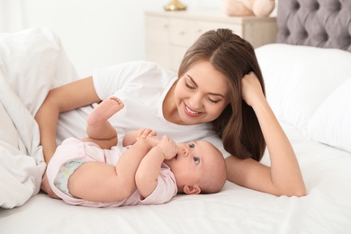 Portrait of mother with her cute baby lying on bed indoors