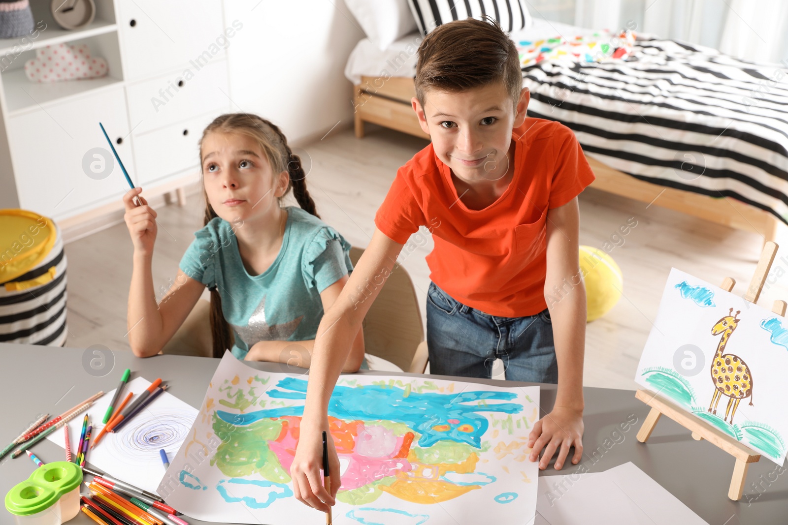 Photo of Little children painting picture at table indoors