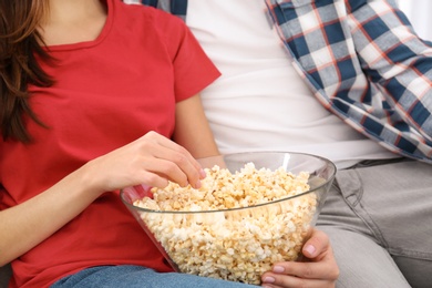 Photo of Young couple watching TV with popcorn on sofa at home