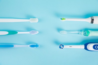 Photo of Electric toothbrushes on light blue background, flat lay