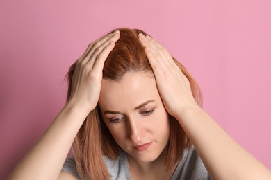 Woman suffering from baldness on pink background