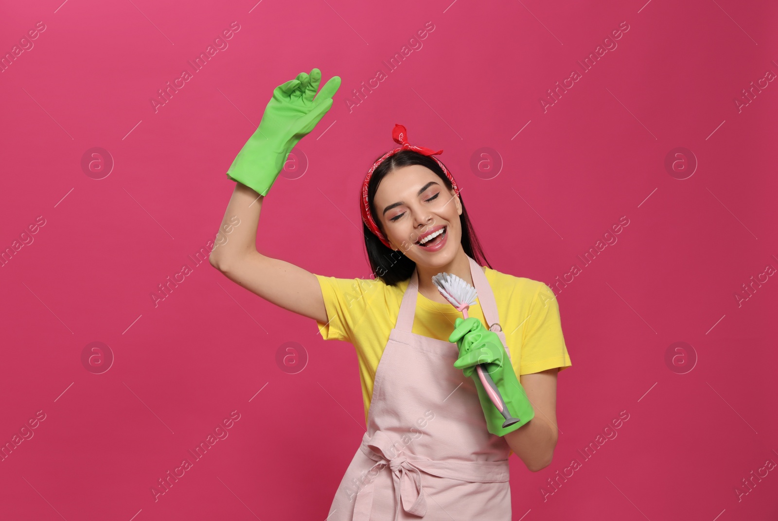 Photo of Young housewife with brush on pink background