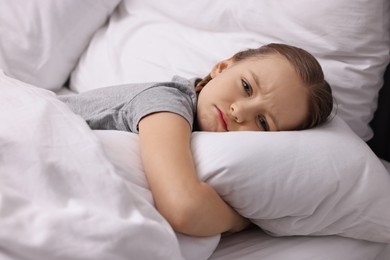 Photo of Little girl suffering from headache in bed