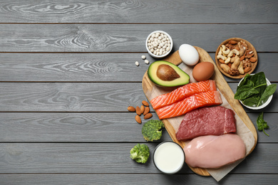 Products rich in protein on grey wooden table, flat lay. Space for text