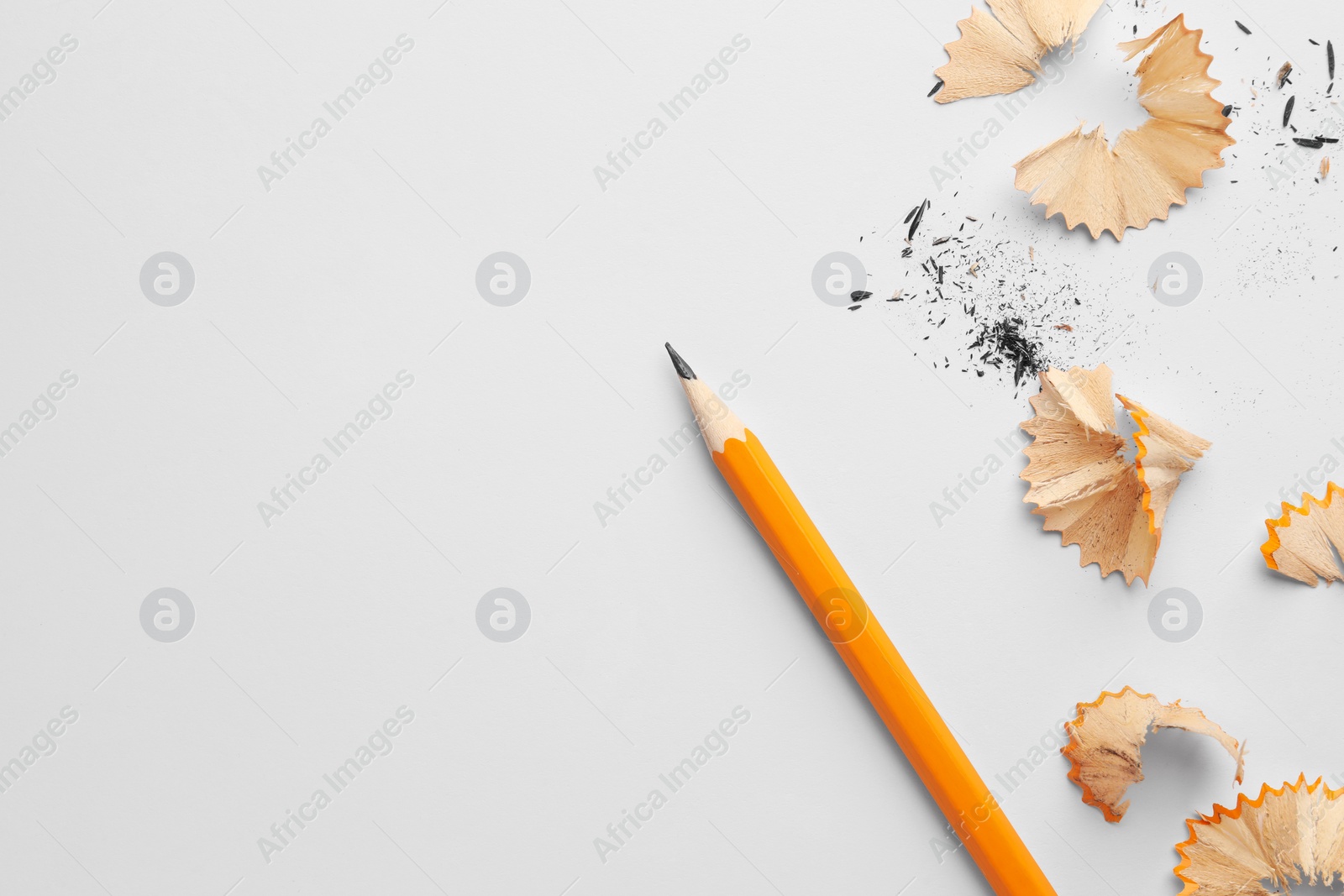 Photo of Graphite pencil and shavings on white background, flat lay. Space for text