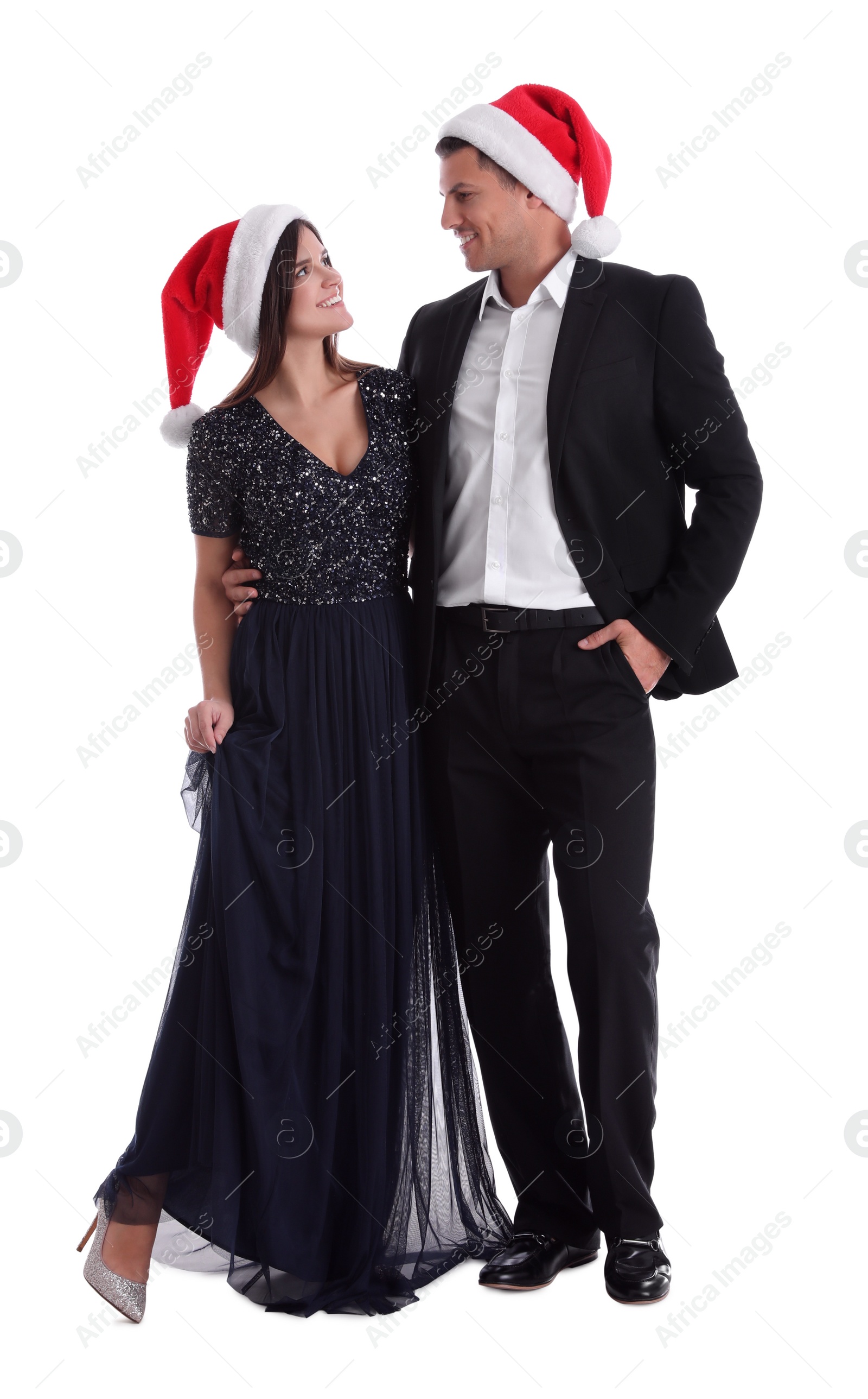 Photo of Beautiful happy couple in Christmas hats on white background