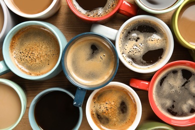 Photo of Cups of fresh aromatic coffee on wooden background, top view. Food photography