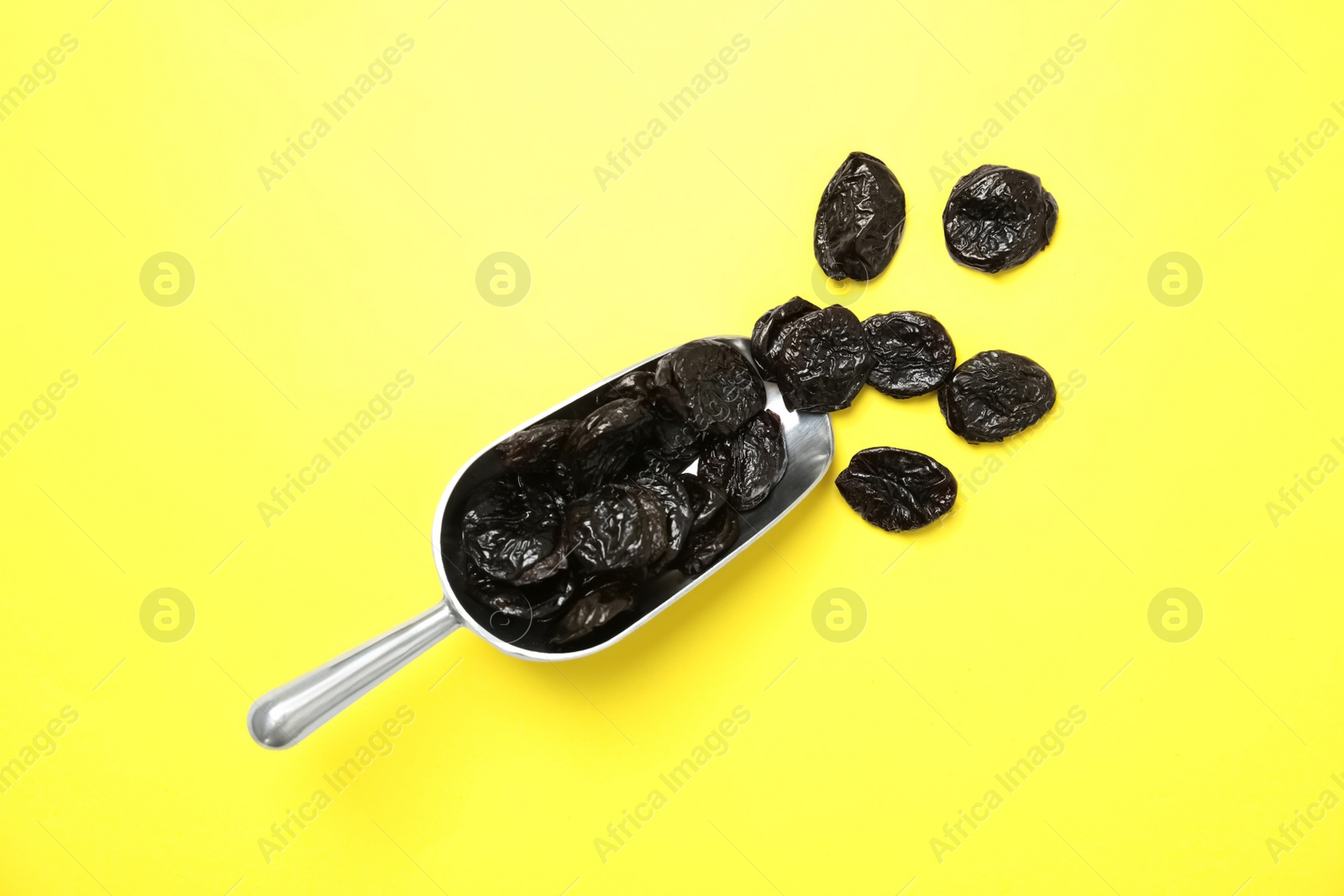 Photo of Scoop of dried plums on color background, top view. Healthy fruit