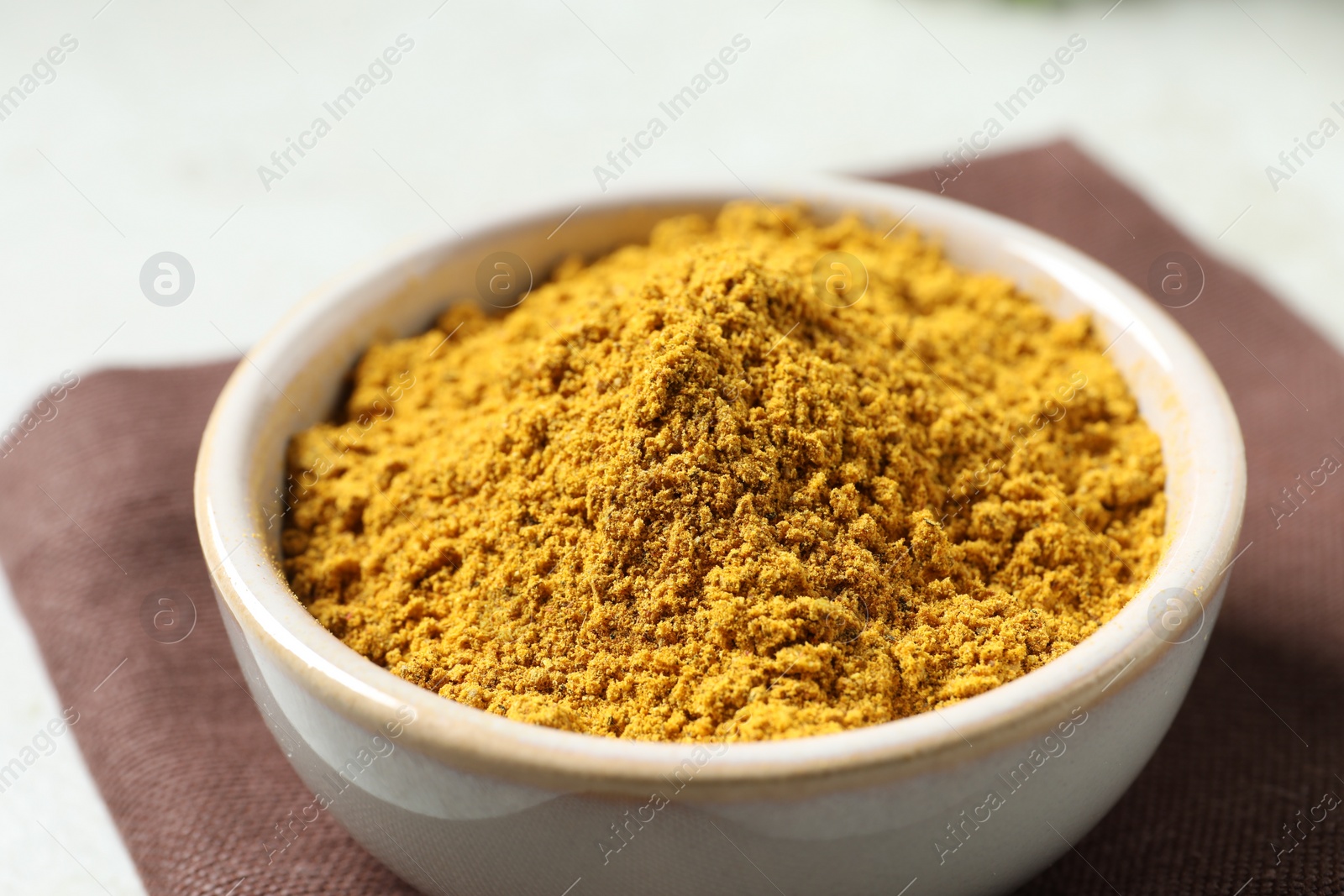 Photo of Curry powder in bowl on white table, closeup