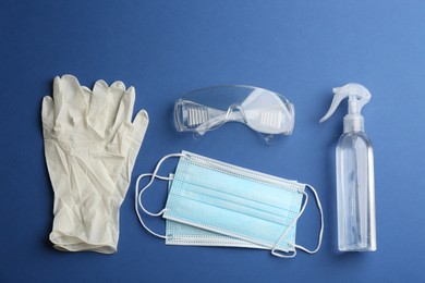 Photo of Flat lay composition with medical gloves, masks and hand sanitizer on blue background