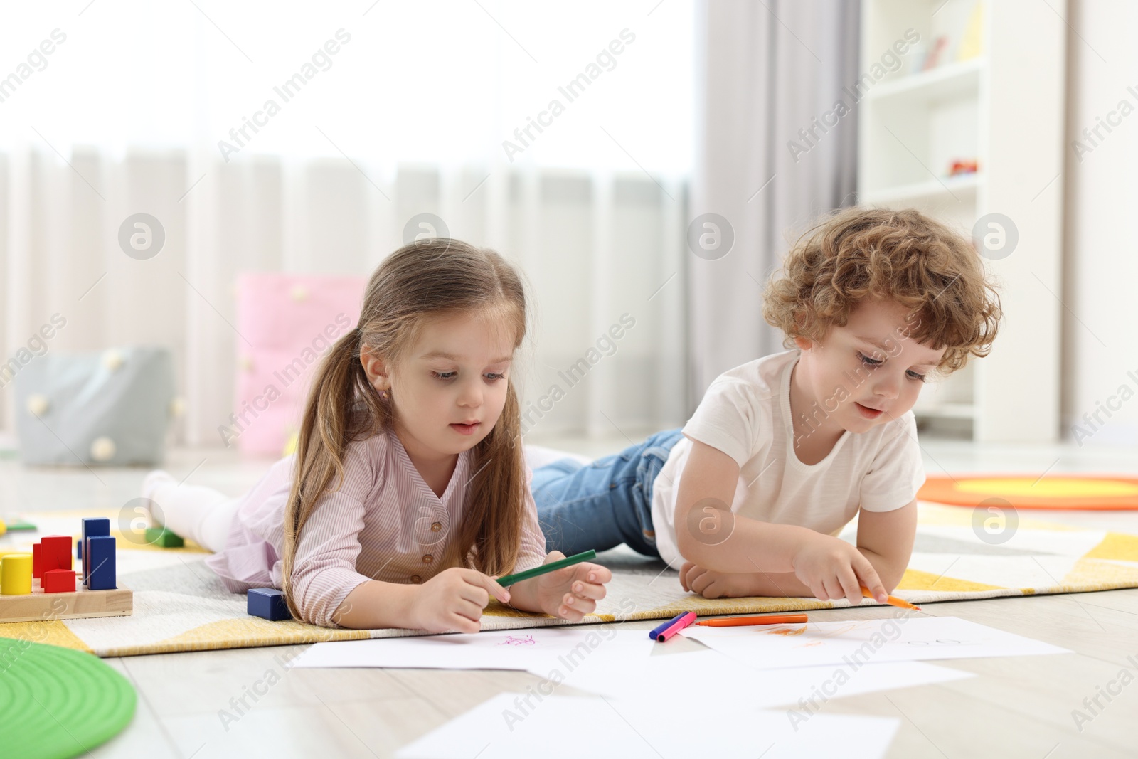 Photo of Cute little children drawing on floor in kindergarten