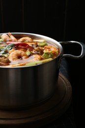 Saucepan with delicious Tom Yum soup on table