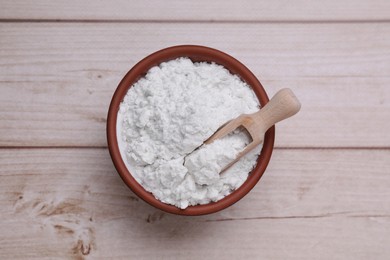 Photo of Bowl and scoop of starch on wooden table, top view