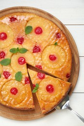 Delicious cut pineapple pie with cherry and mint on white wooden table, top view