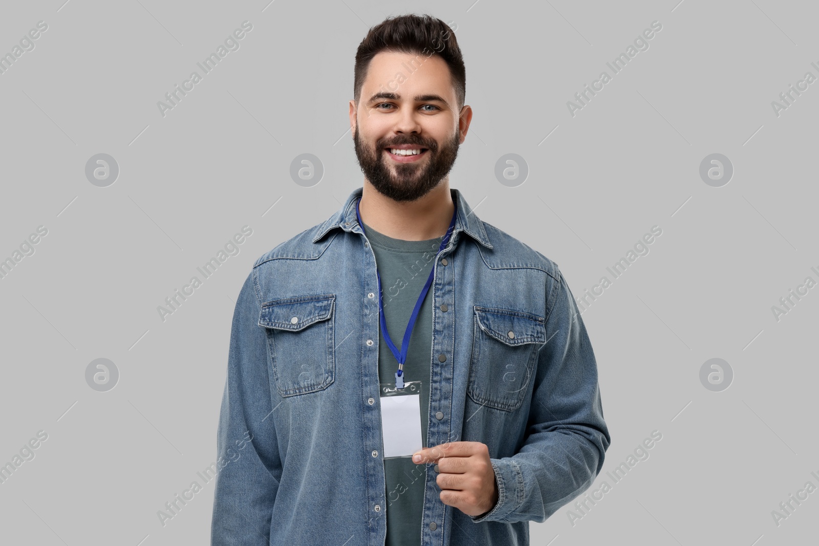 Photo of Happy young man with blank badge on grey background