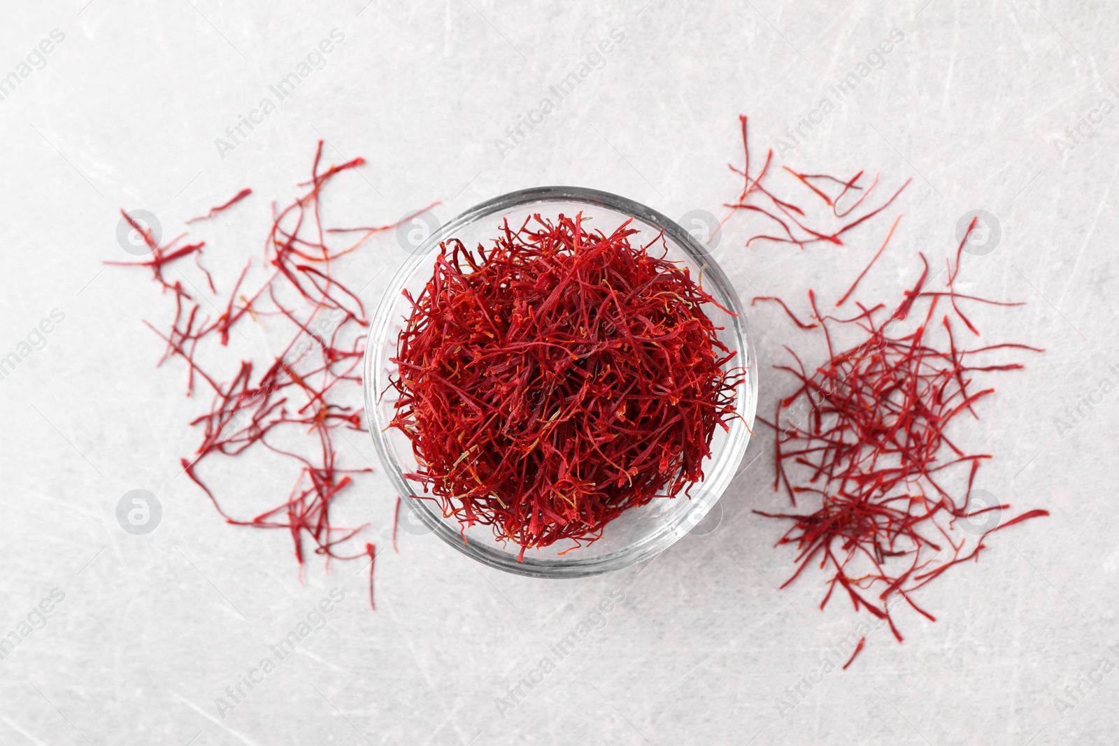 Photo of Dried saffron and glass bowl on grey table, flat lay