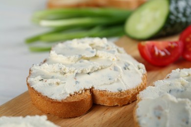 Photo of Toasted bread with cream cheese on wooden board, closeup