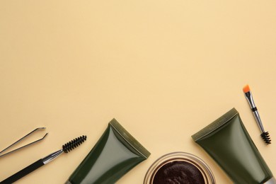 Flat lay composition with eyebrow henna and tools on beige background. Space for text