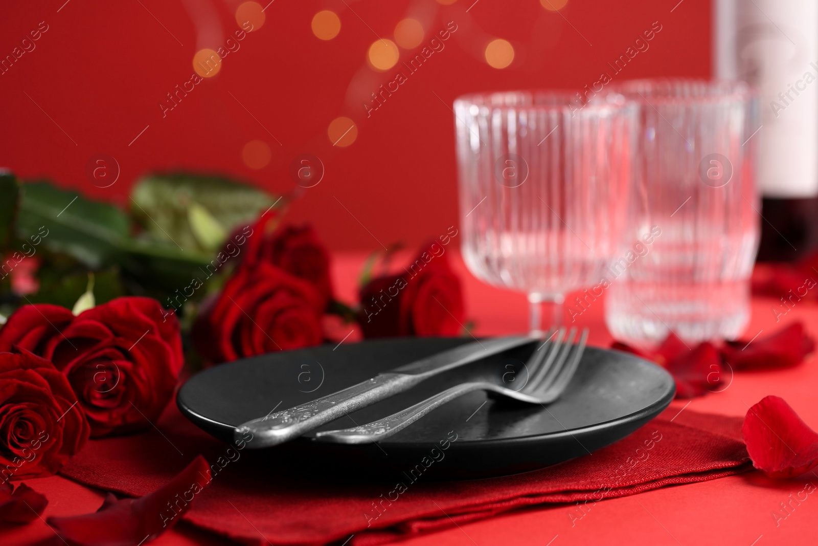 Photo of Place setting with roses on red table, closeup. Romantic dinner
