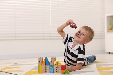 Cute little boy playing with wooden toys indoors, space for text