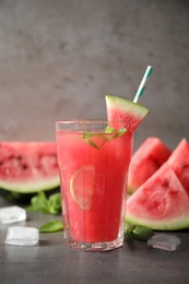 Photo of Glass of tasty refreshing drink with watermelon on grey table