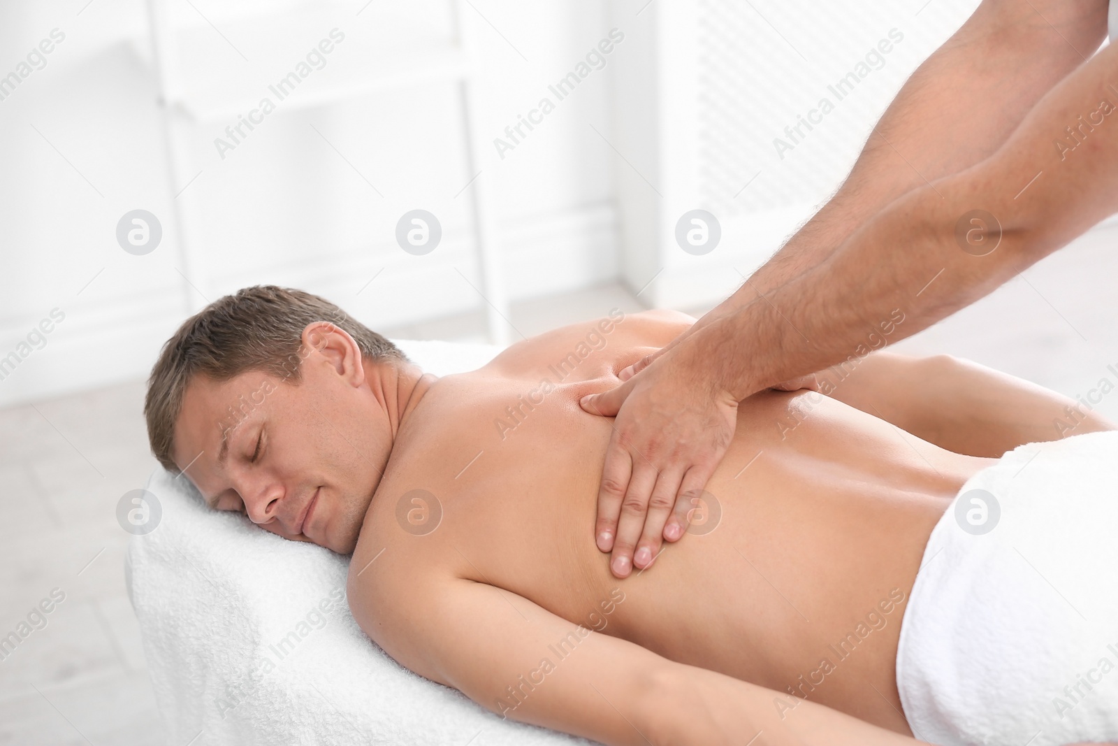 Photo of Relaxed man receiving back massage in wellness center