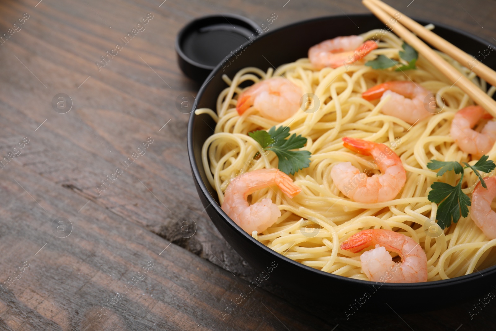 Photo of Tasty spaghetti with shrimps, parsley and soy sauce on wooden table, closeup. Space for text