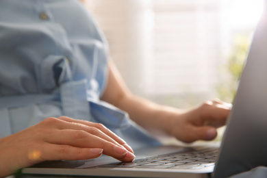 Woman working with modern laptop indoors, closeup