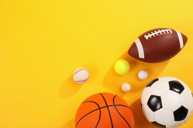 Photo of Many different sports balls on yellow background, flat lay. Space for text