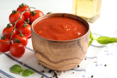 Photo of Bowl of tasty tomato sauce on table, closeup