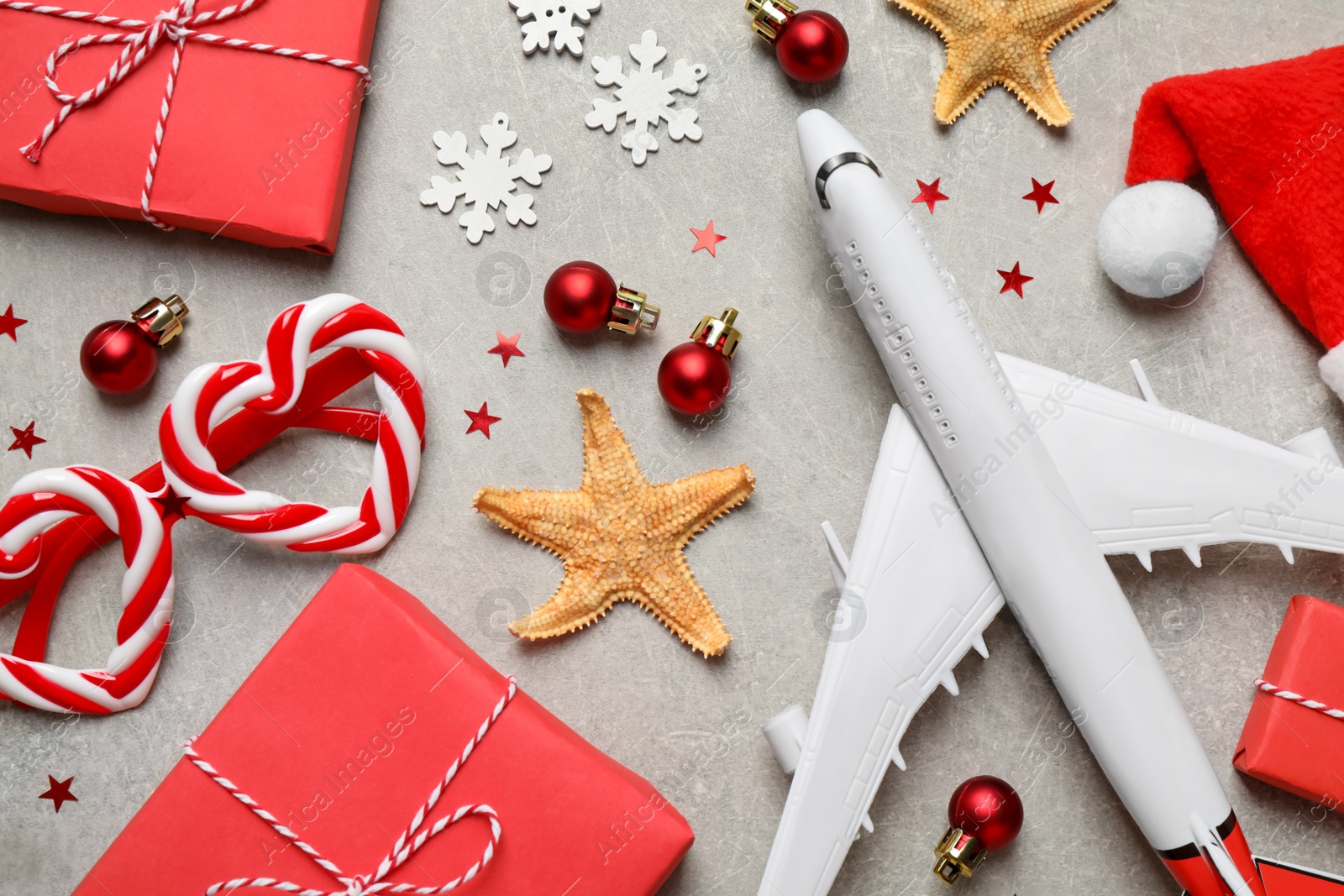 Photo of Flat lay composition with Christmas decorations and toy airplane on light table. Winter vacation