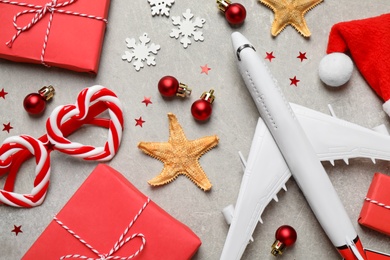 Photo of Flat lay composition with Christmas decorations and toy airplane on light table. Winter vacation