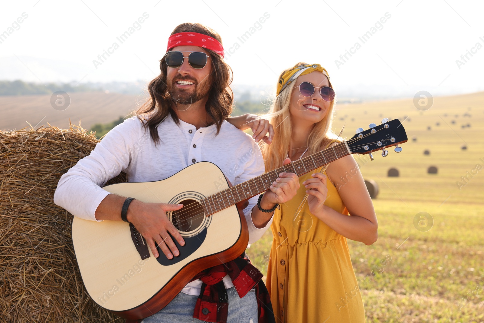 Photo of Beautiful hippie woman listening to her friend playing guitar in field