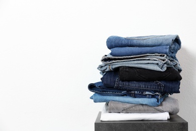 Stack of different jeans on table against white background. Space for text