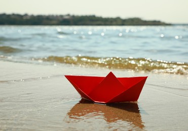 Photo of Red paper boat near river on sunny day