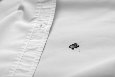 Photo of Stain of black ink on white shirt, closeup. Space for text
