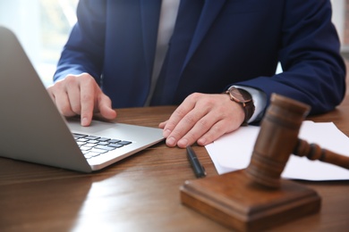 Photo of Notary working with laptop at table in office, closeup. Law and justice concept