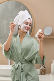 Woman applying face mask in bathroom. Spa treatments