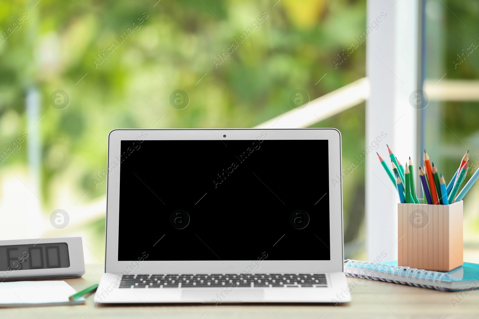 Photo of Modern laptop on table against window. Mock up with space for text