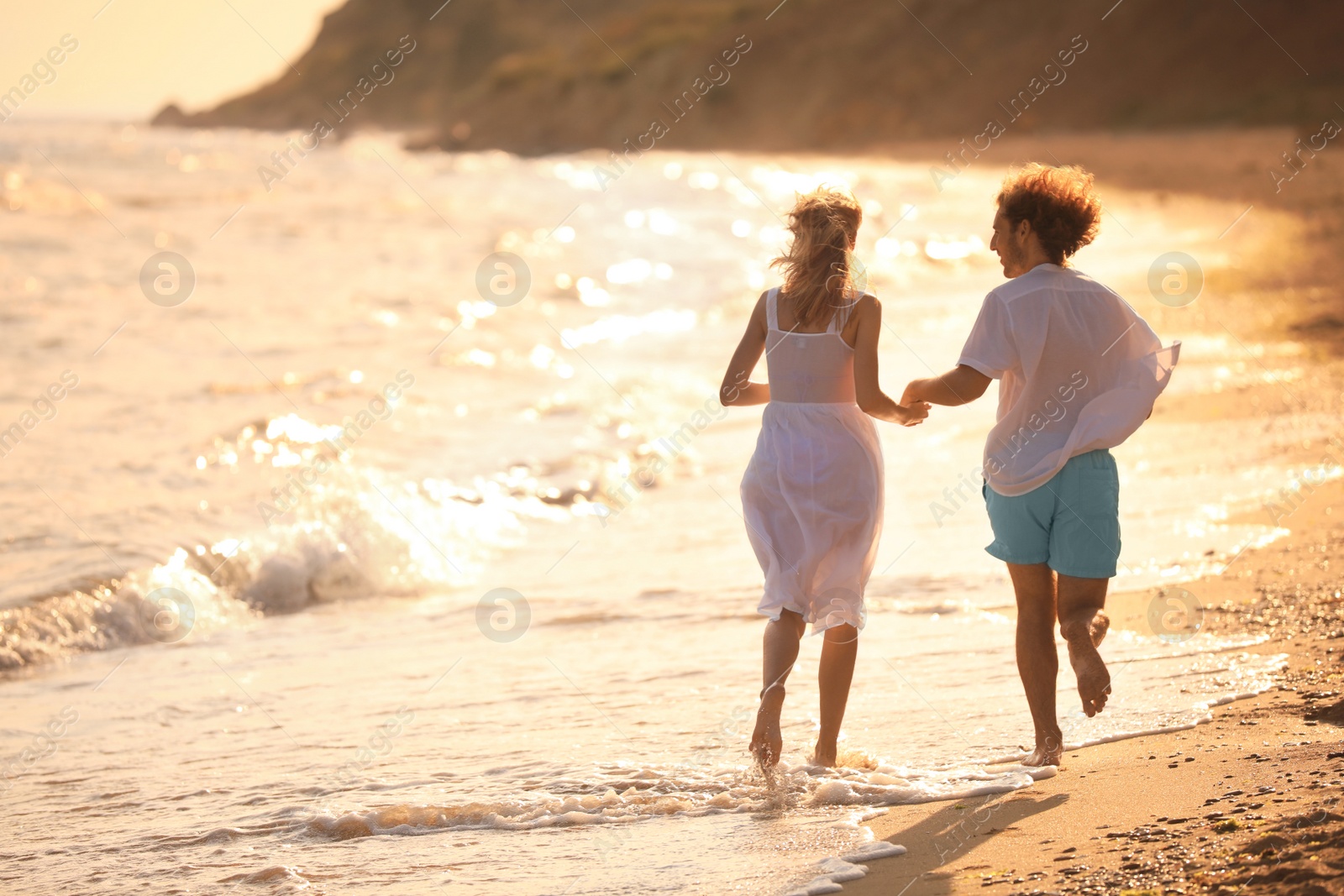 Photo of Young couple walking on beach at sunset