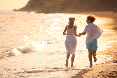 Photo of Young couple walking on beach at sunset