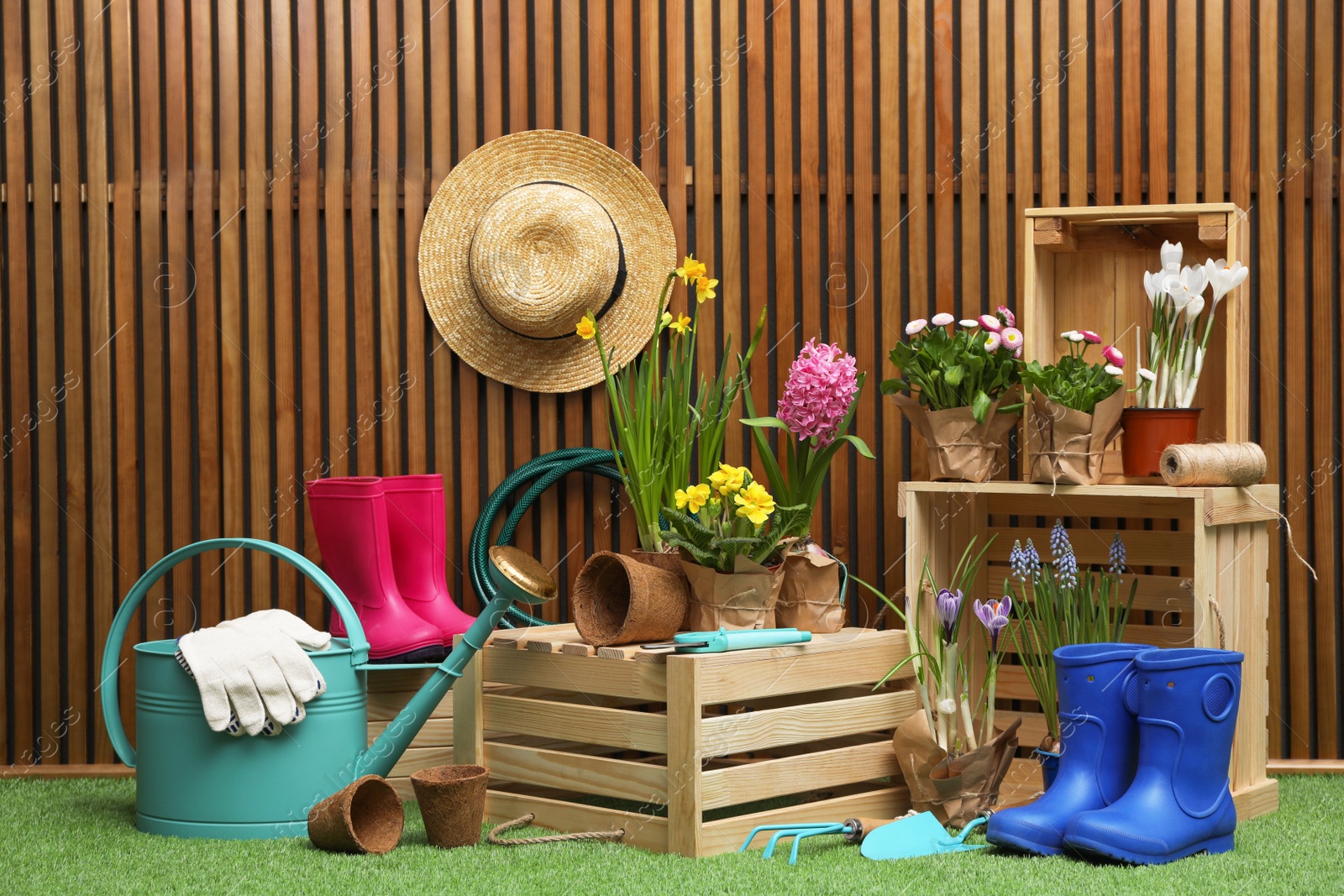 Photo of Composition with different gardening tools on artificial grass at wooden wall