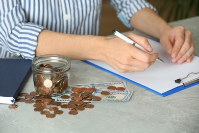 Photo of Woman counting coins at table, closeup. Money savings