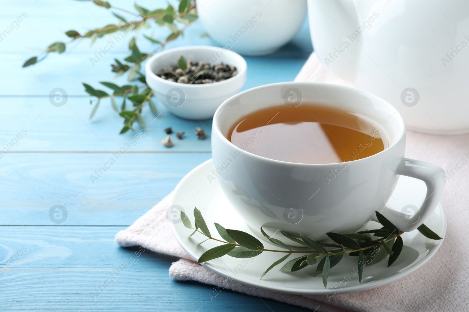 Photo of Cup of aromatic eucalyptus tea on light blue wooden table. Space for text