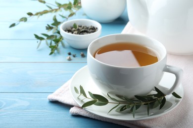 Photo of Cup of aromatic eucalyptus tea on light blue wooden table. Space for text