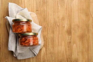 Photo of Delicious kimchi with Chinese cabbage on wooden table, flat lay. Space for text