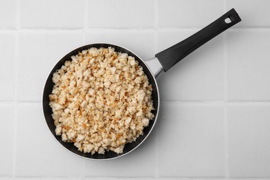 Photo of Fried ground meat in frying pan on white tiled table, top view. Space for text